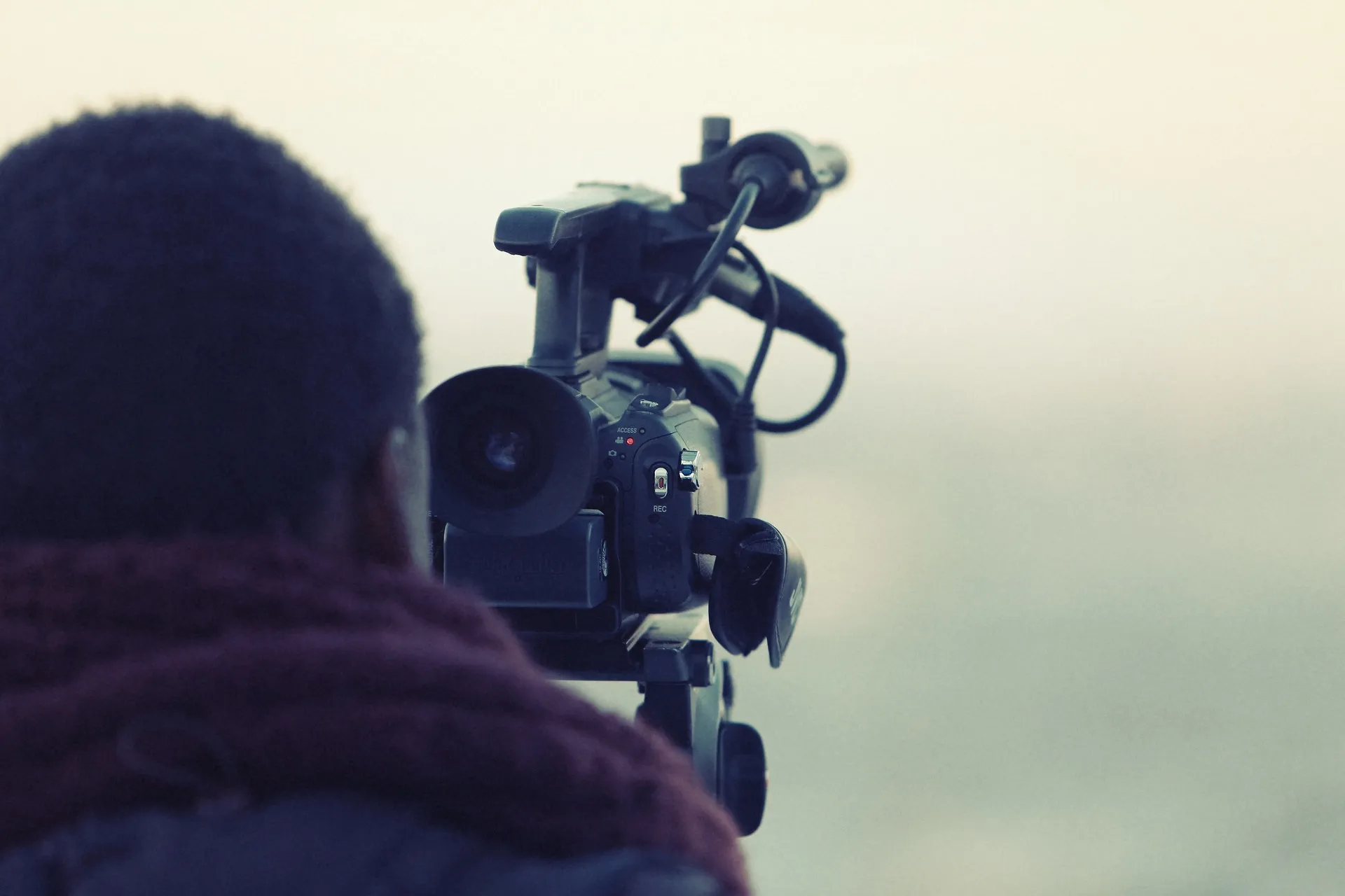 A camera operator silhouetted against an open sky