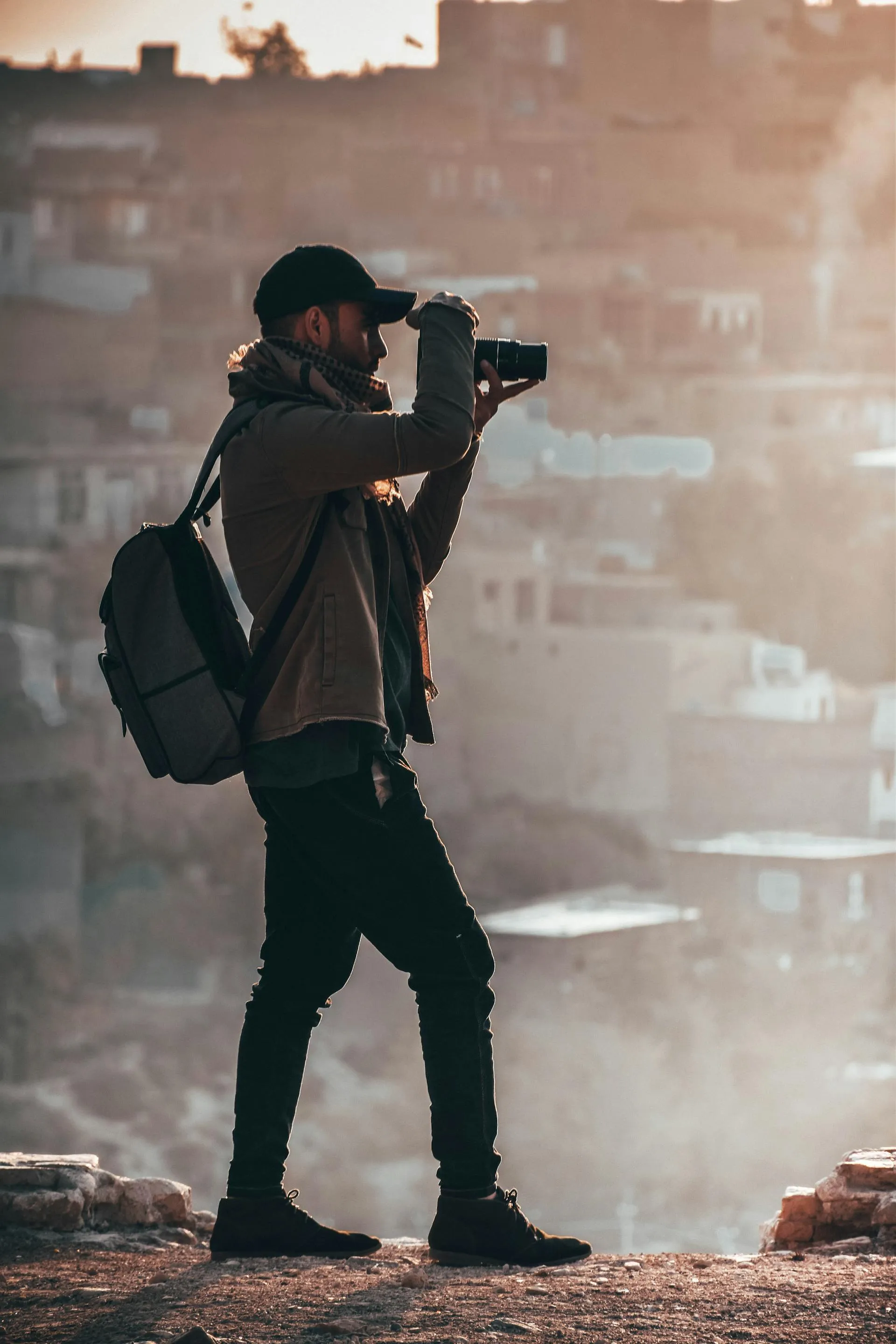 A photographer overlooking a hillside city at golden hour
