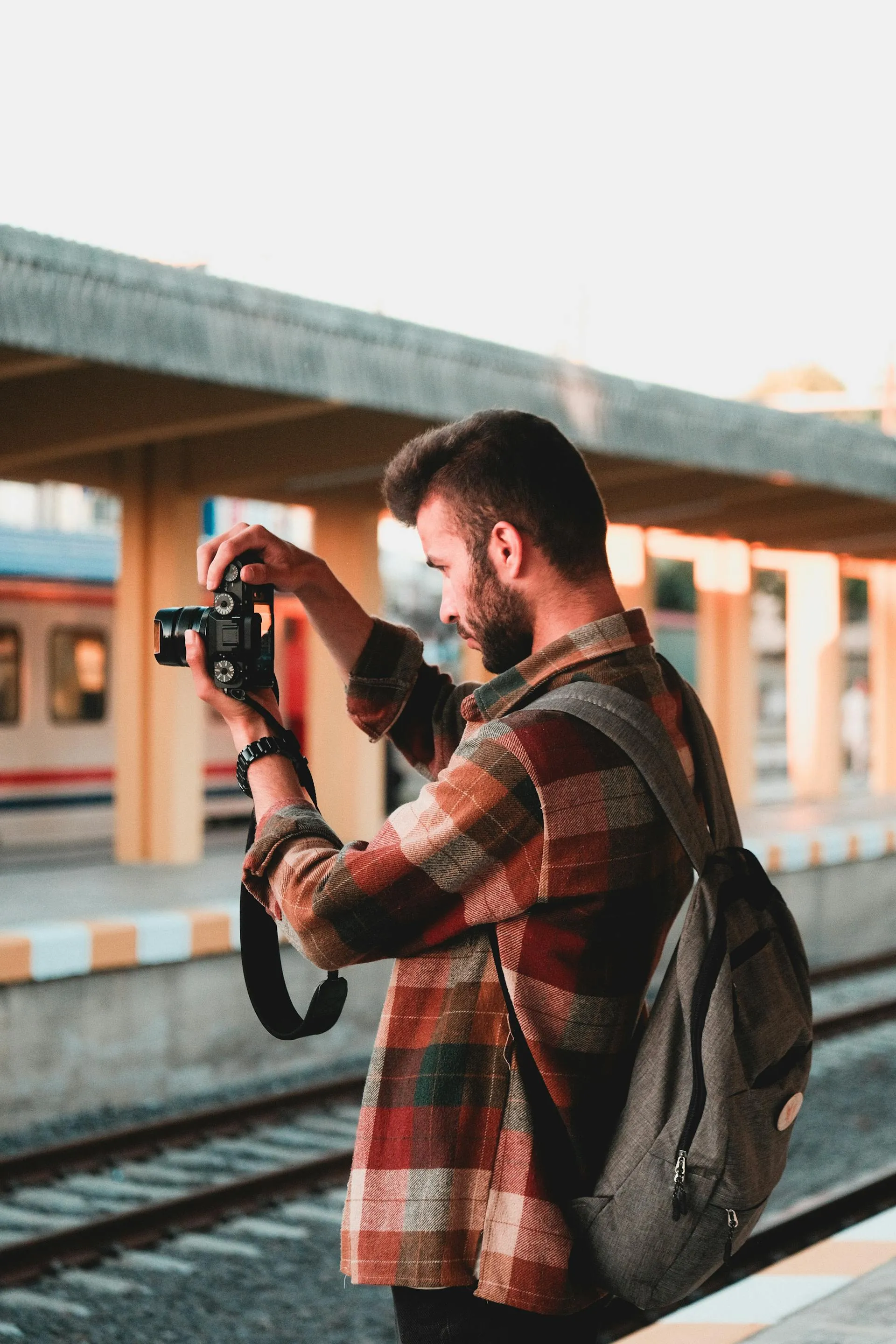 A photographer raising a camera to take a photo at a train station