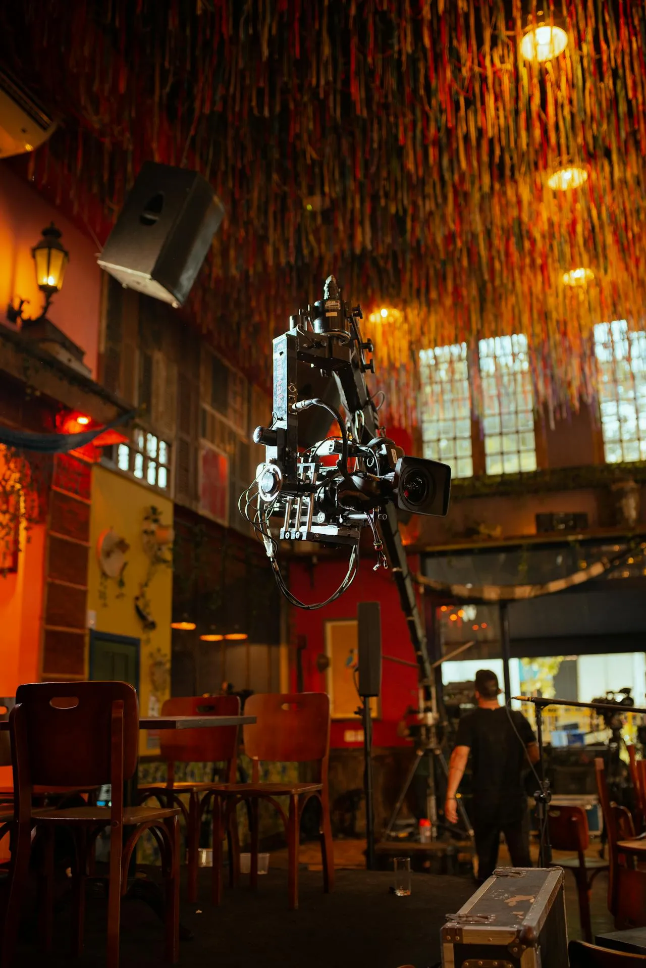 A camera crane rig positioned on a film set inside a warmly lit venue