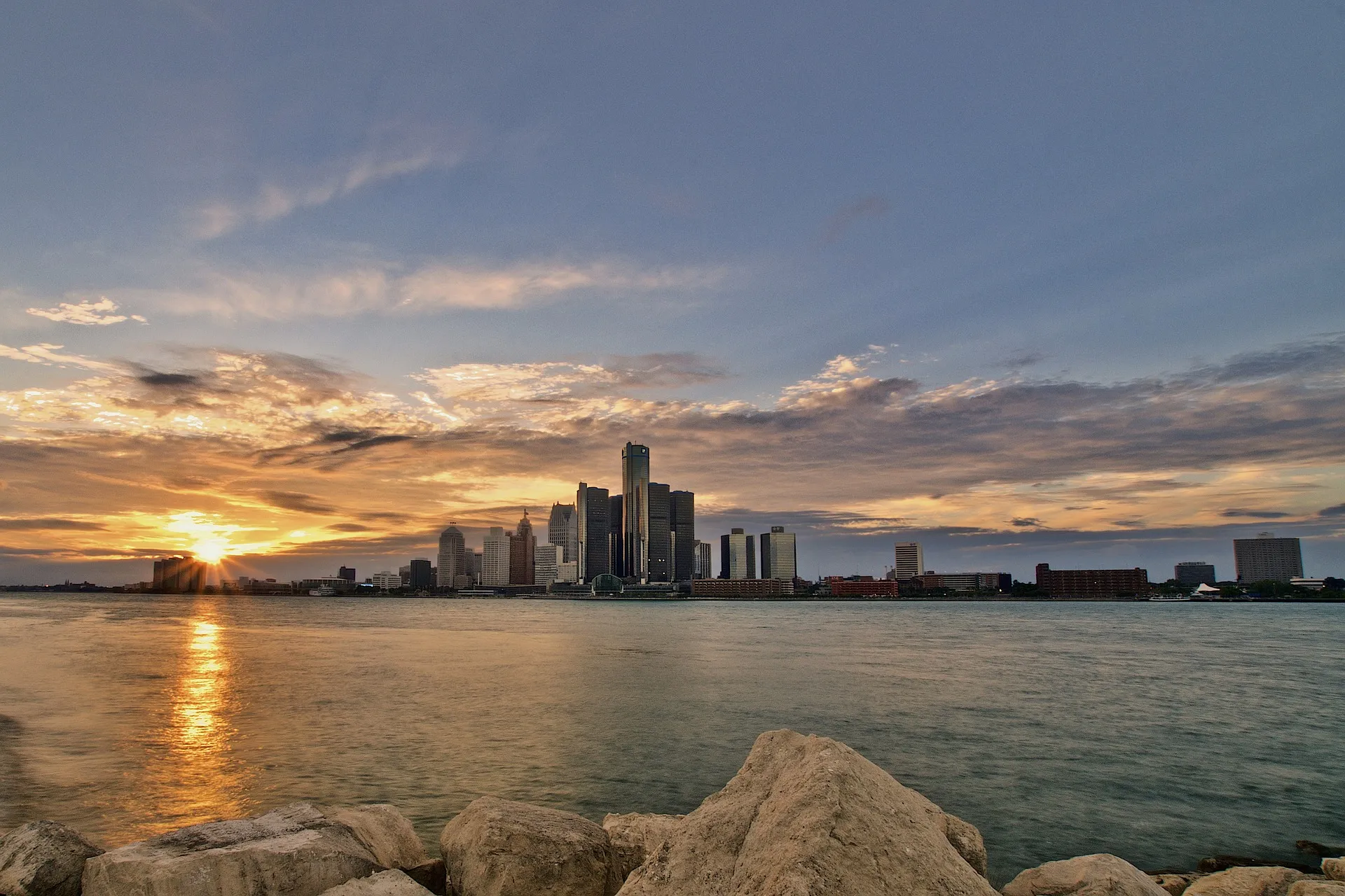 The Detroit skyline silhouetted against a dramatic sunset over the water