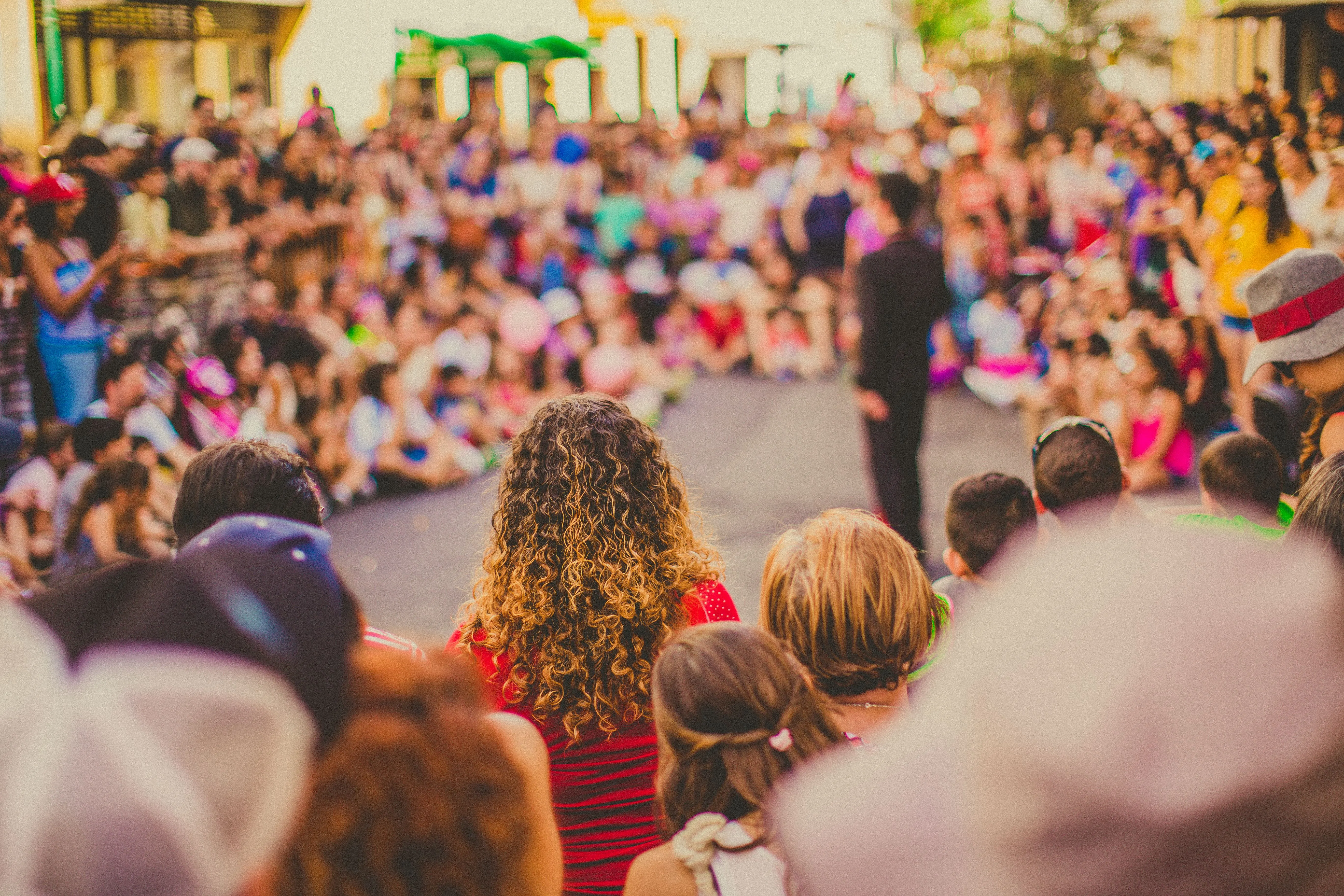 A crowd gathered closely together, watching a performer at a community street event