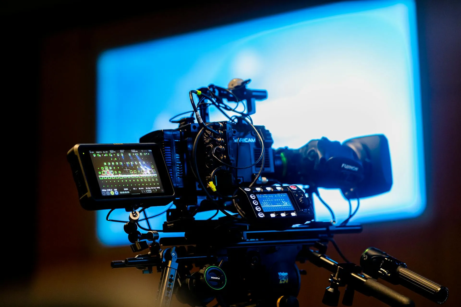 A cinema camera rig with monitor, set up against a blue studio backdrop