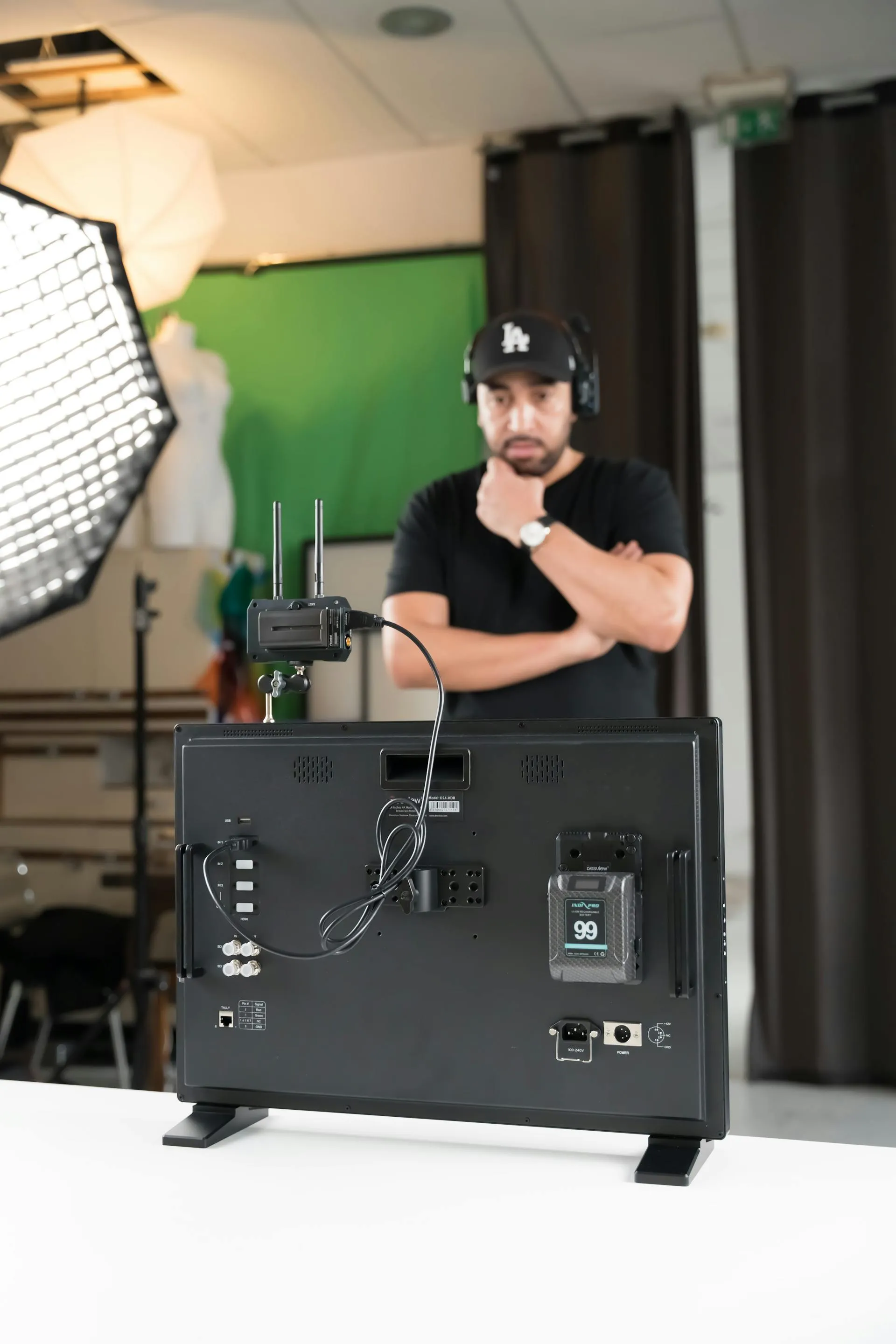A production monitor and playback deck on set with a crew member in the background