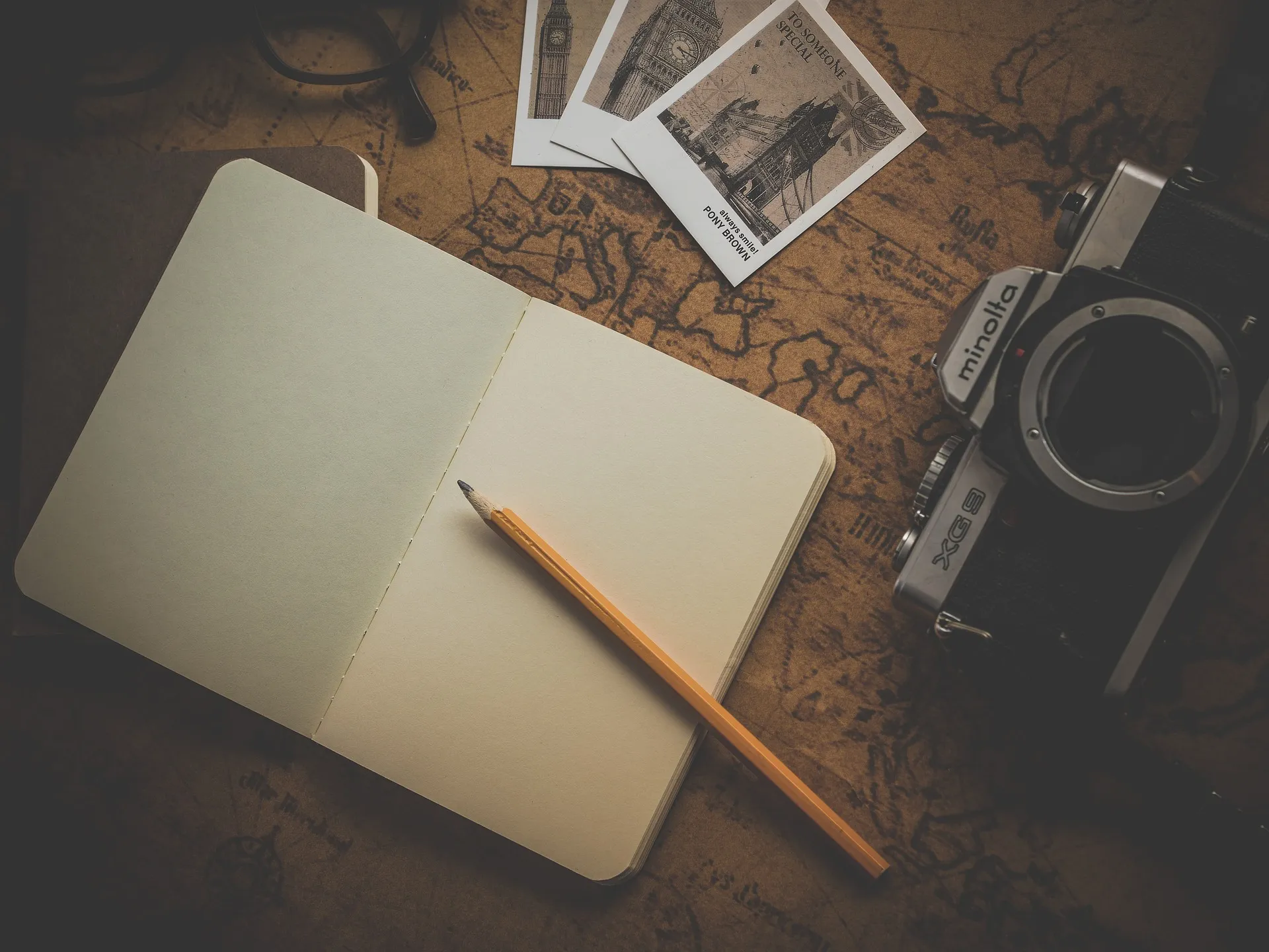 A journal, pencil, and vintage camera laid out on a map, ready for planning