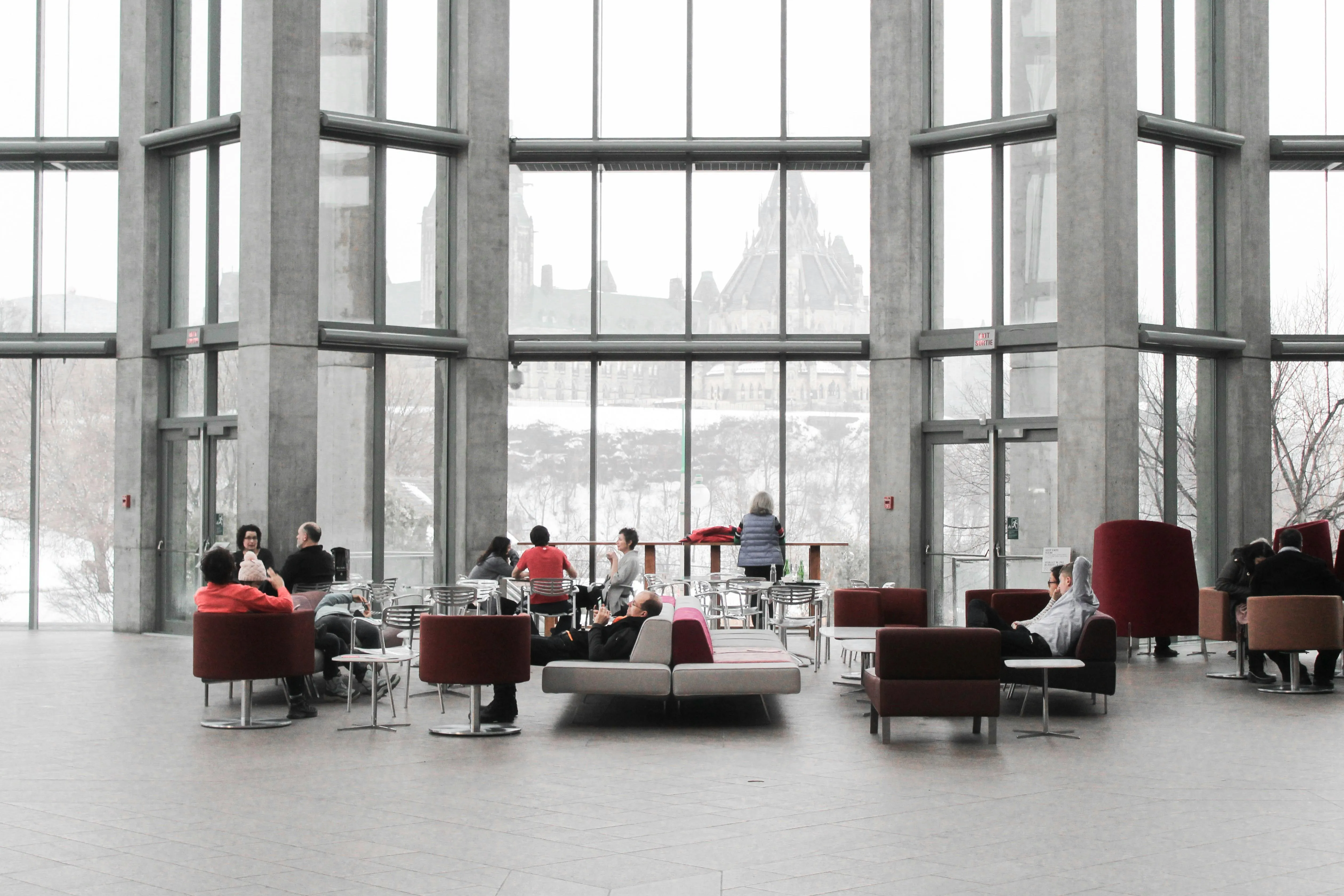 A bright, glass-walled gathering space with small groups seated and talking